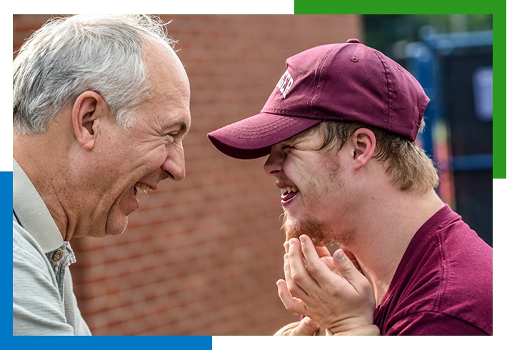 Two men laughing and looking at each other.