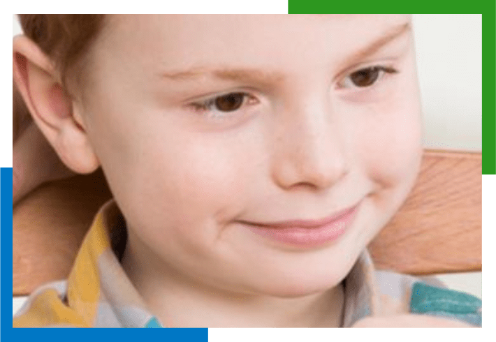 Young boy smiling with a plaid shirt.